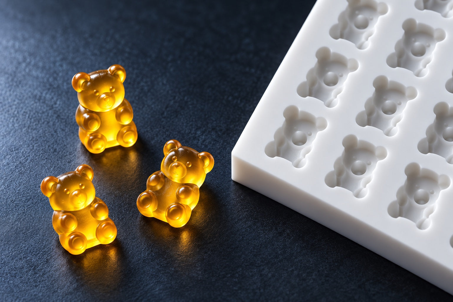 Amber gummy bears beside a white silicone mold, illustrative studio scene